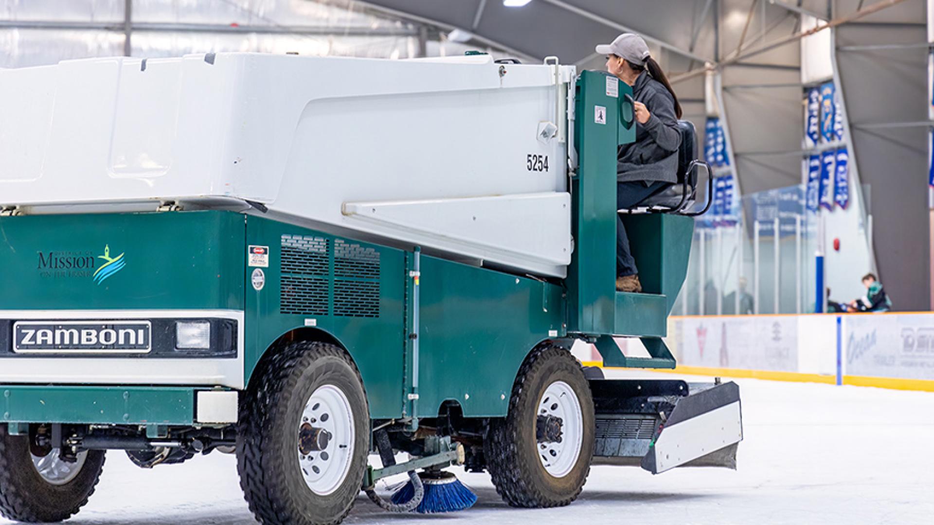 Female staff zamboni driver cleaning ice